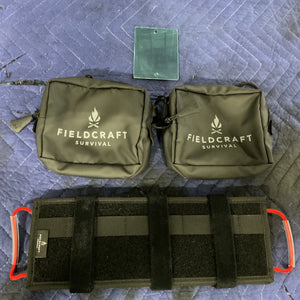 Fieldcraft Survival Modular Visor Panel with two black gear pouches on a blue quilted surface