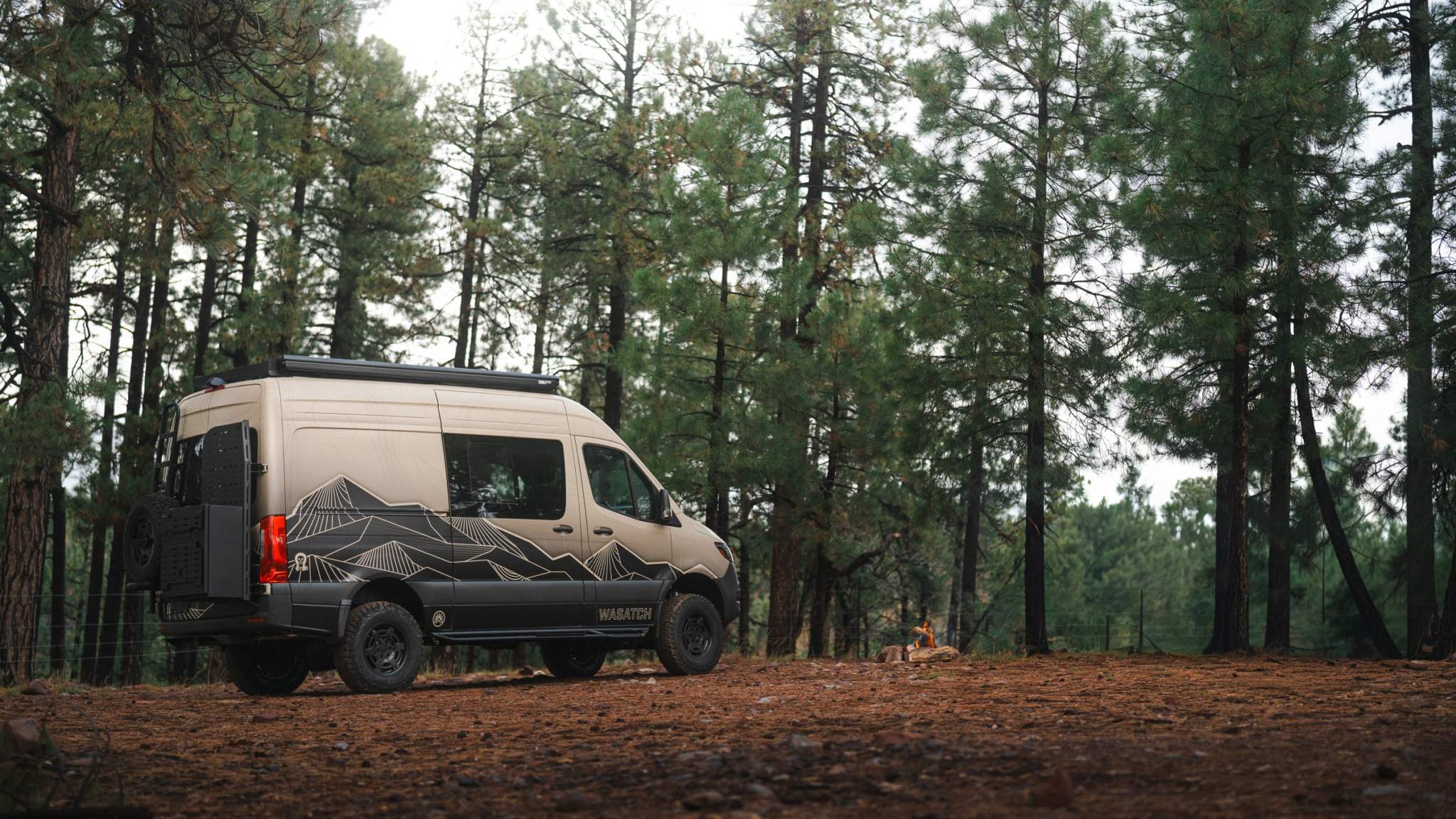 Owl x VanCraft Wasatch Halo Sprinter van with mountain design parked in forest camping setting
