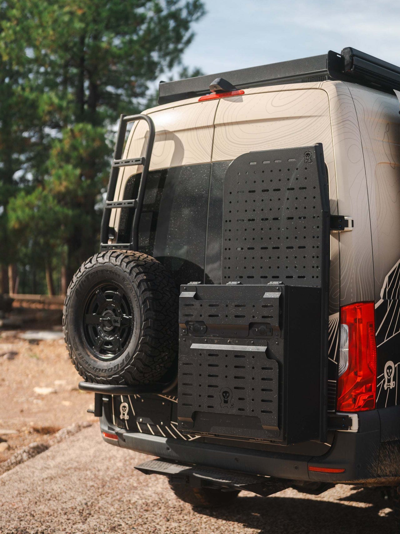 Owl x VanCraft Wasatch Halo Sprinter van rear with spare tire and accessory mounts in outdoor setting