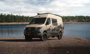Owl x VanCraft Wasatch Halo Sprinter van with mountain graphics parked by lake in wilderness