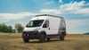 White Promaster van equipped with matte black Talon wheels on a grassy field under a partly cloudy sky