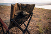 Tan ergonomic camp chair with mesh storage pocket set outdoors near lake at sunset
