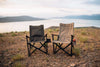 Two ergonomic camp chairs in tan and olive colors set on rocky terrain overlooking a lake and mountains at sunset