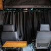 Black insulated Sprinter curtain with magnetic tabs installed between van cab and living area for privacy and temperature control.