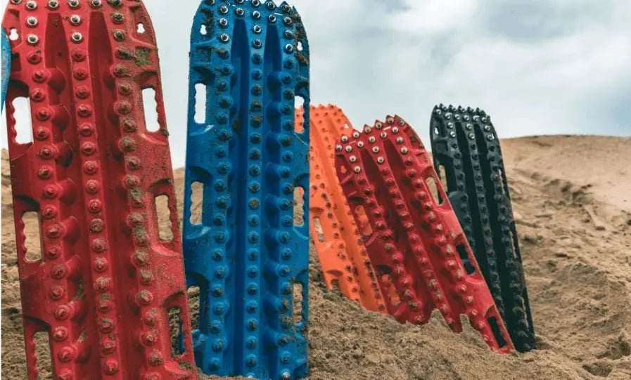Traction boards with steel pins in sand for off-road use.