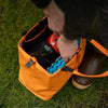 RUX 25L Bag orange versatile storage bag being packed outdoors on grass