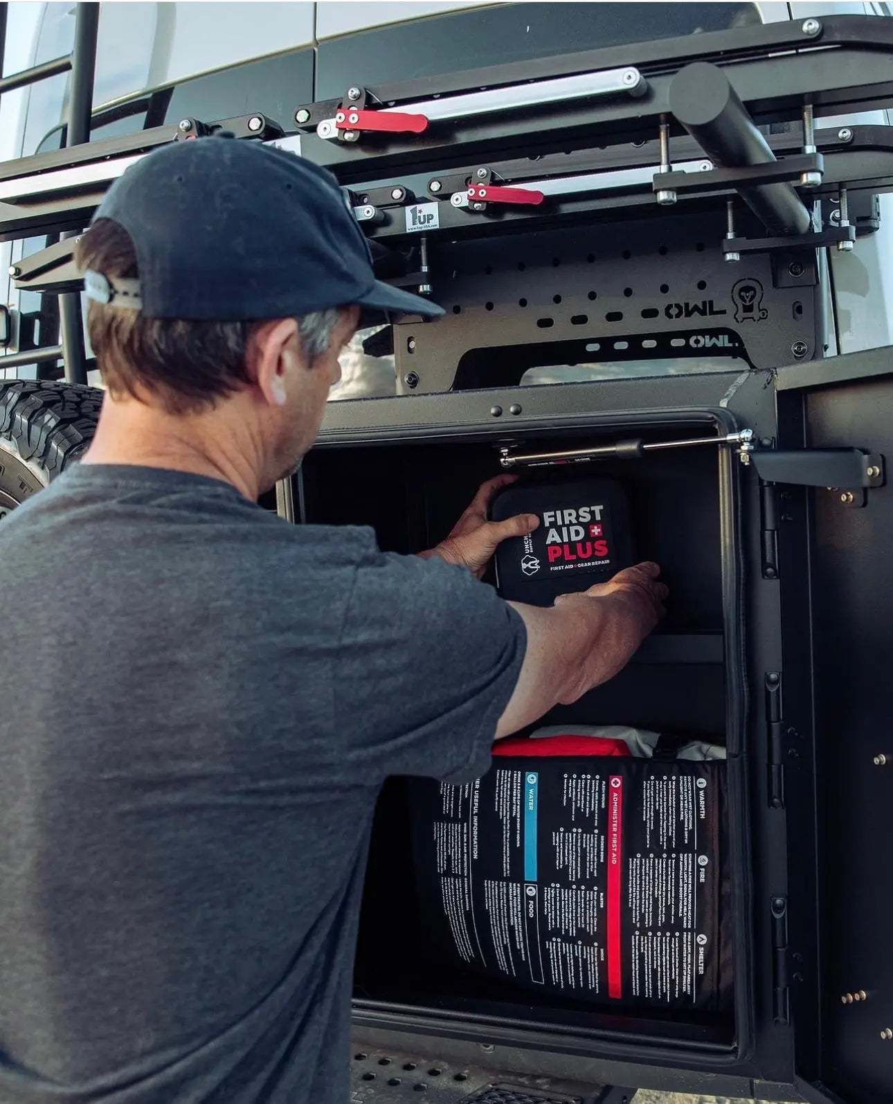 Man organizing contents in Expedition Box - Large, mounted on Owl carrier, showcasing durable black aluminum construction and adjustable shelf.