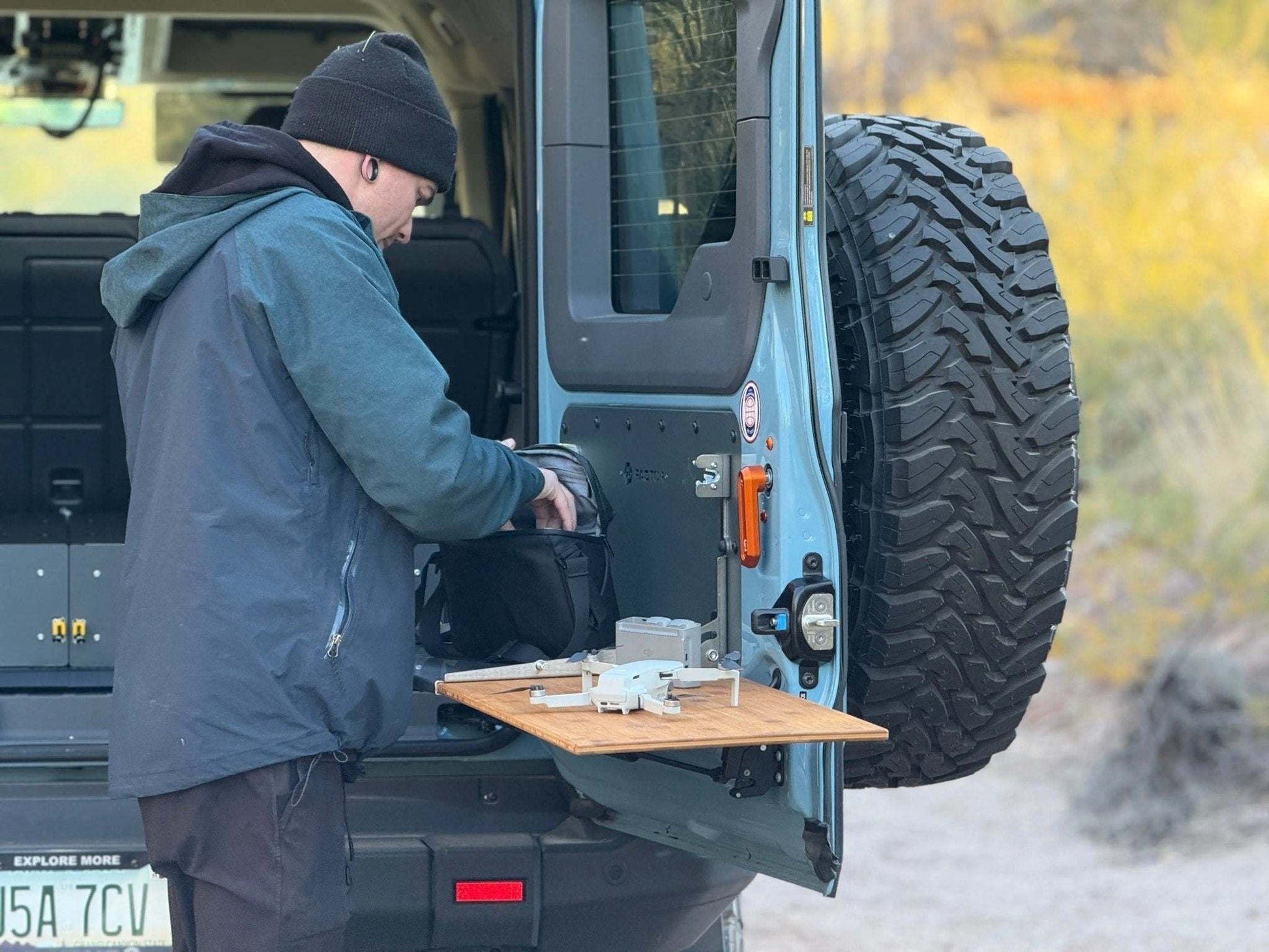 Folding tailgate table installed on INEOS Grenadier with person using it outdoors.