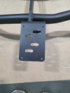 Close-up of black Grenadier Bullbar mounting bracket with precision cutouts on a textured surface