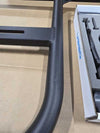 Close-up of black powder-coated aluminum Sprinter Tire Carrier with bolt-on hoop and mounting bracket on cardboard background