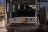 Side X Side Drawer Module installed in the rear cargo area of an off-road vehicle with one drawer open showing wooden interior and durable exterior panels