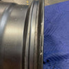 Graphite grey Owl Talon Sprinter wheel with minor scuffs, shown laying on a blue quilted surface.