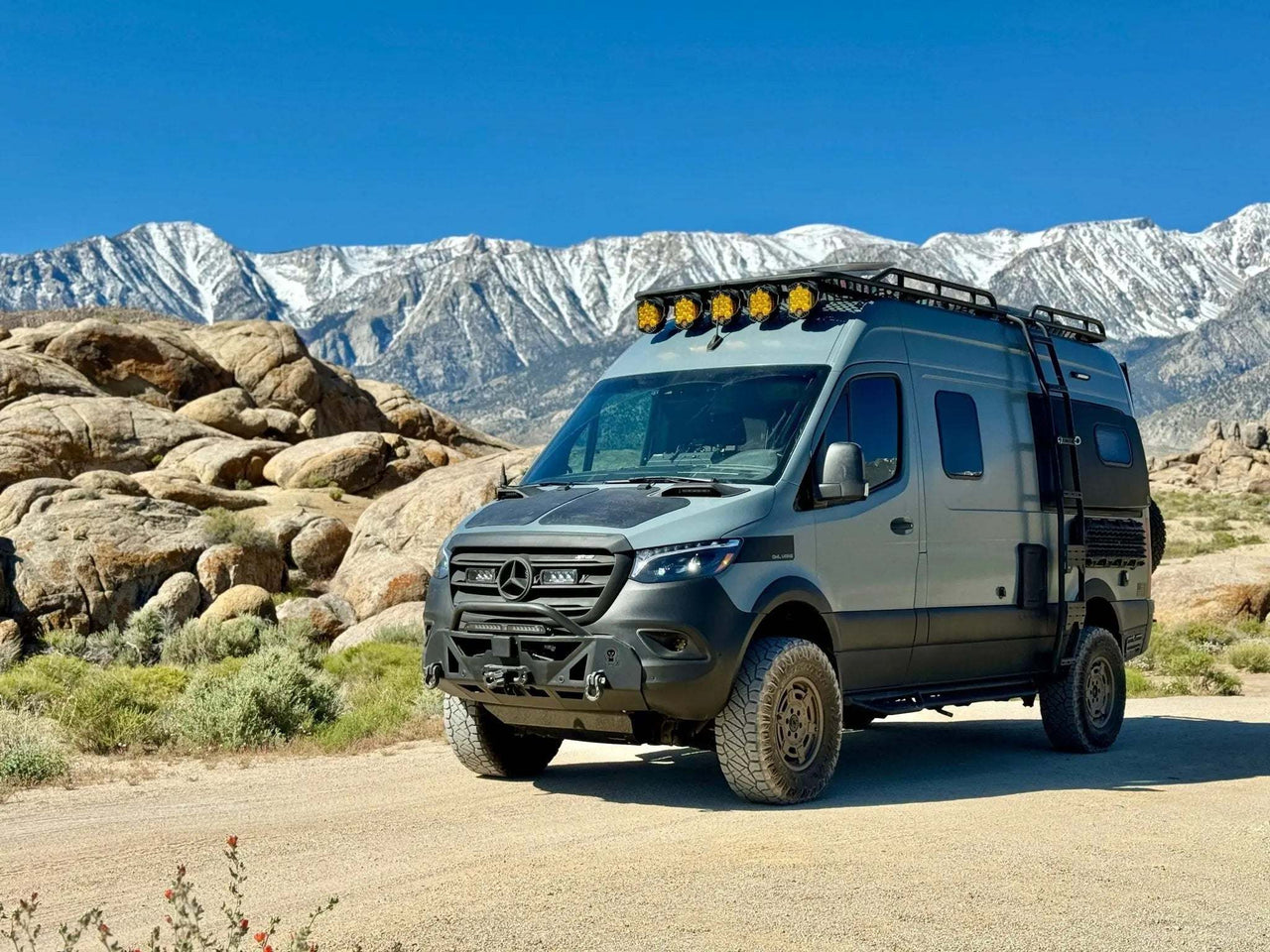 Aero Sprinter Hood Spoiler on 2019+ Sprinter enhances aerodynamics and protects from debris, set against a mountain backdrop.