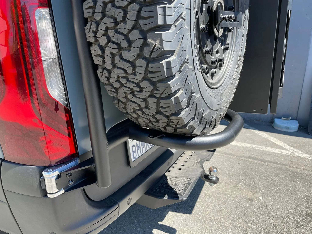 Low-angle view of Owl Sprinter Rear Door Tire Carrier with spare tire on Mercedes Sprinter van