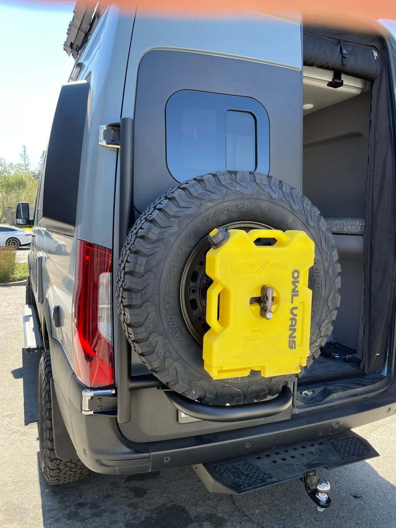 Owl Sprinter Tire Carrier with full-size spare tire and yellow fuel container on expedition van