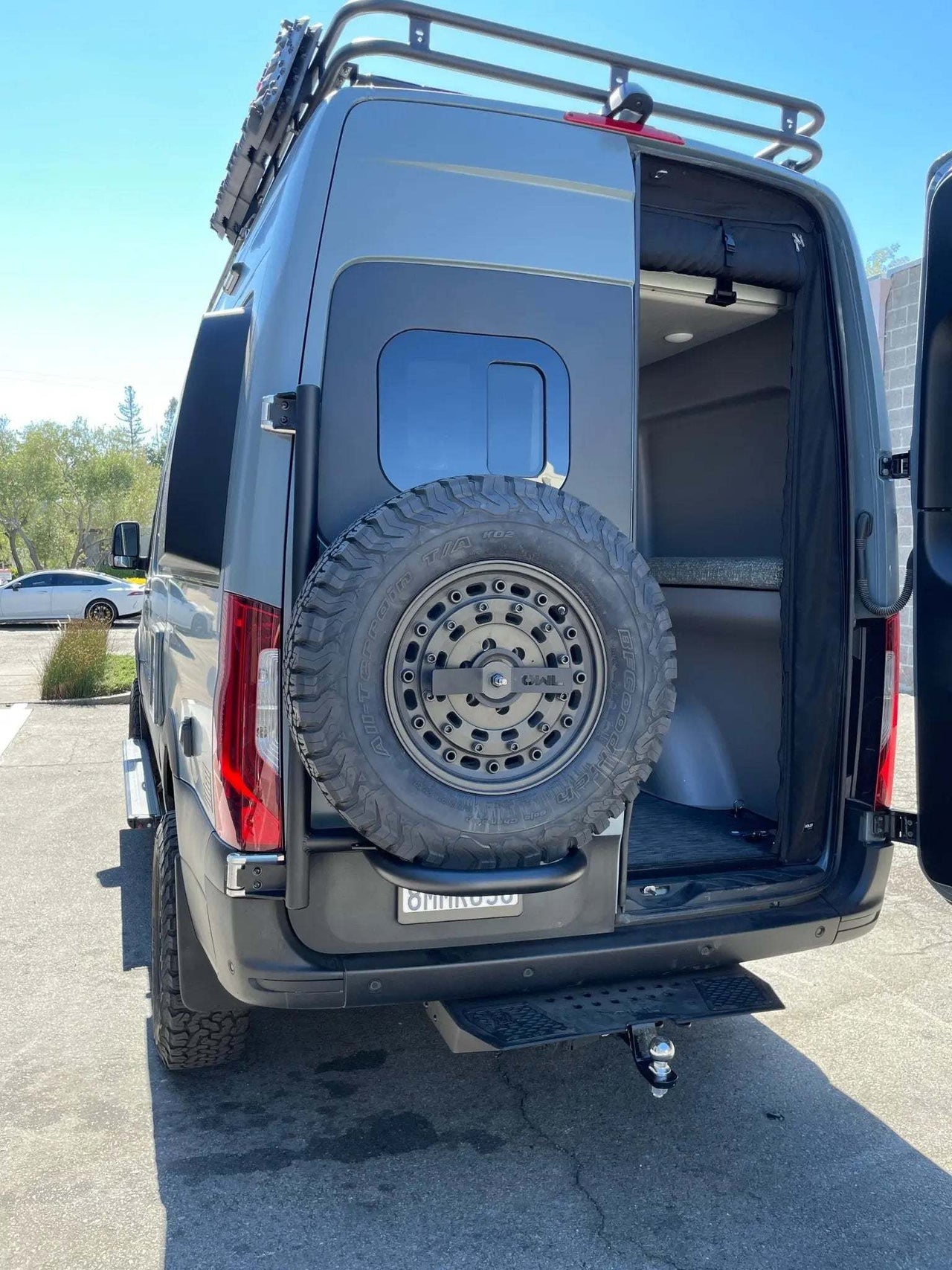 Owl Sprinter Tire Carrier with open rear door and full-size spare tire on black expedition van