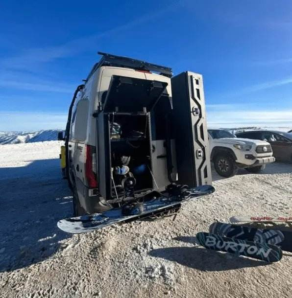 Van Storage Box Monster 40 mounted on open van door with snowboard gear outdoors