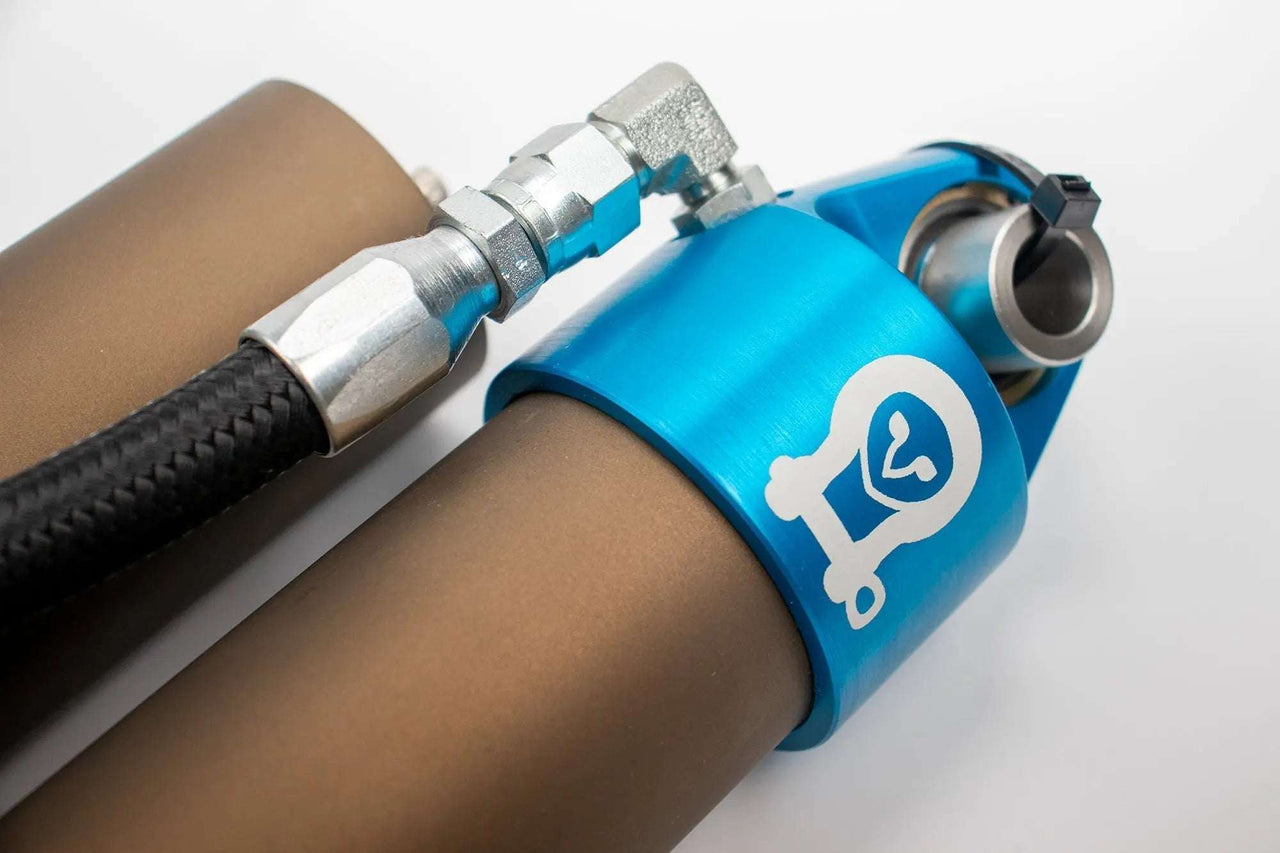 Grenadier Suspension - Close-up of Owl 4" Lift TrailFlo Suspension component with blue anodized part and hose fitting for
