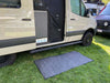 Small outdoor area rug in front of camper van.