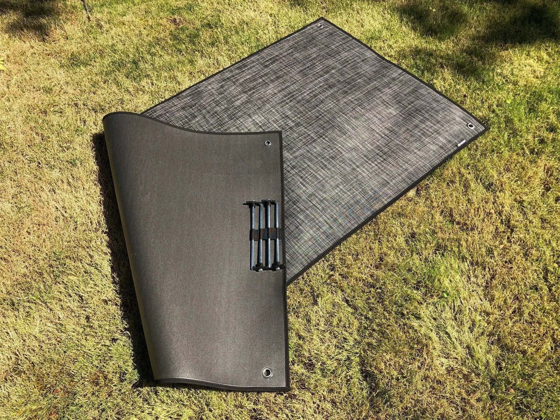 Small outdoor area rug on grass, suitable for camping and outdoor use.