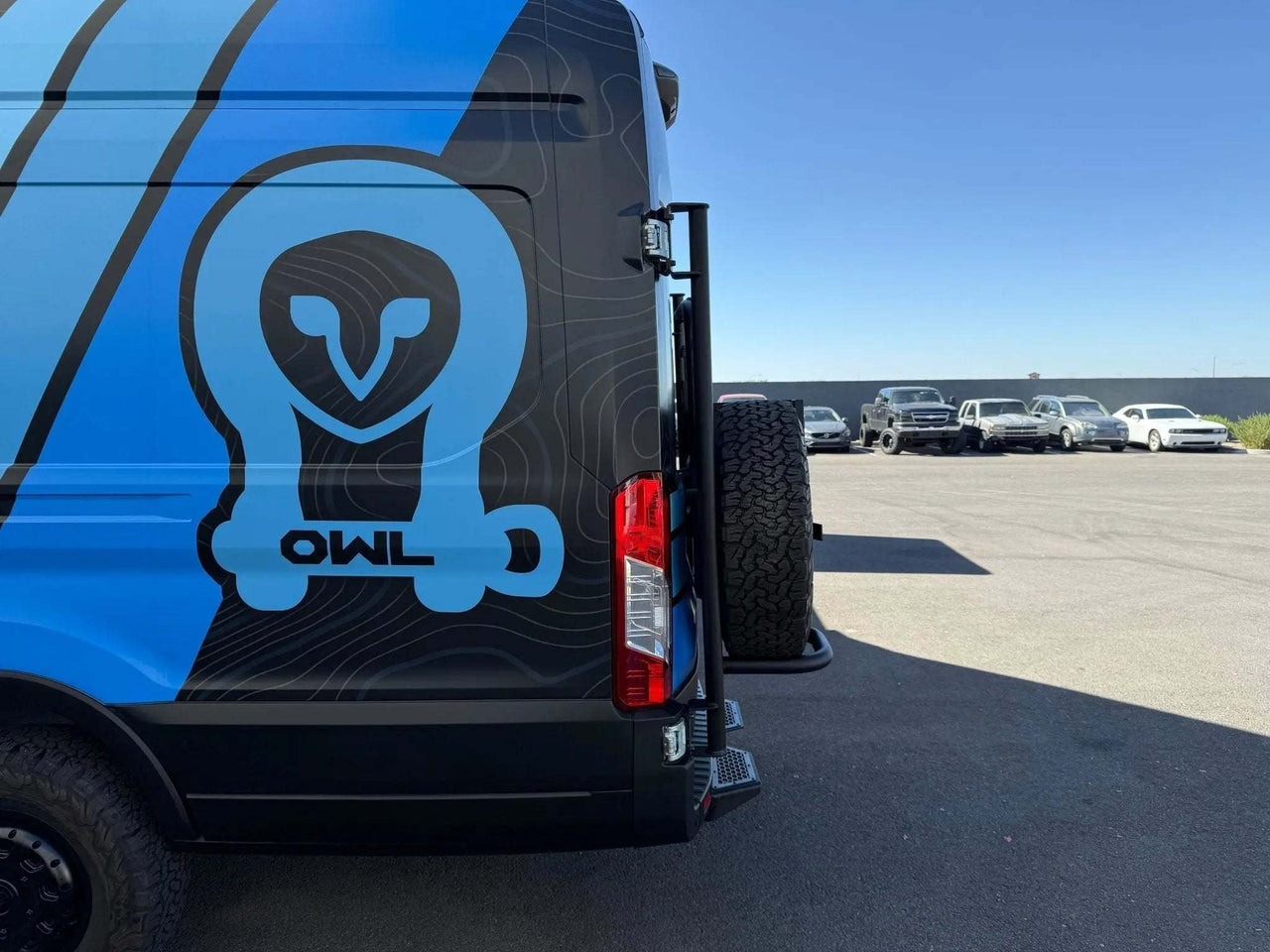 Side view of a Ford Transit with an Owl tire carrier on the rear doors