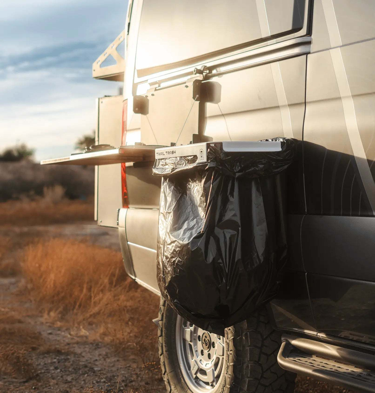 Magnetic Trail Trash holder attached to off-road vehicle with black trash bag outdoors at sunset