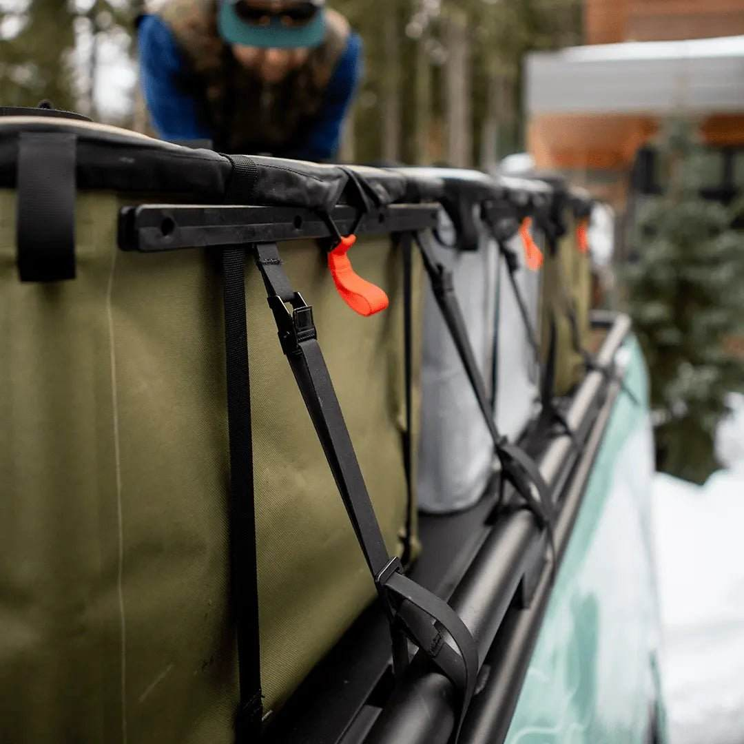 Tie-down straps securing gear on a vehicle roof rack.