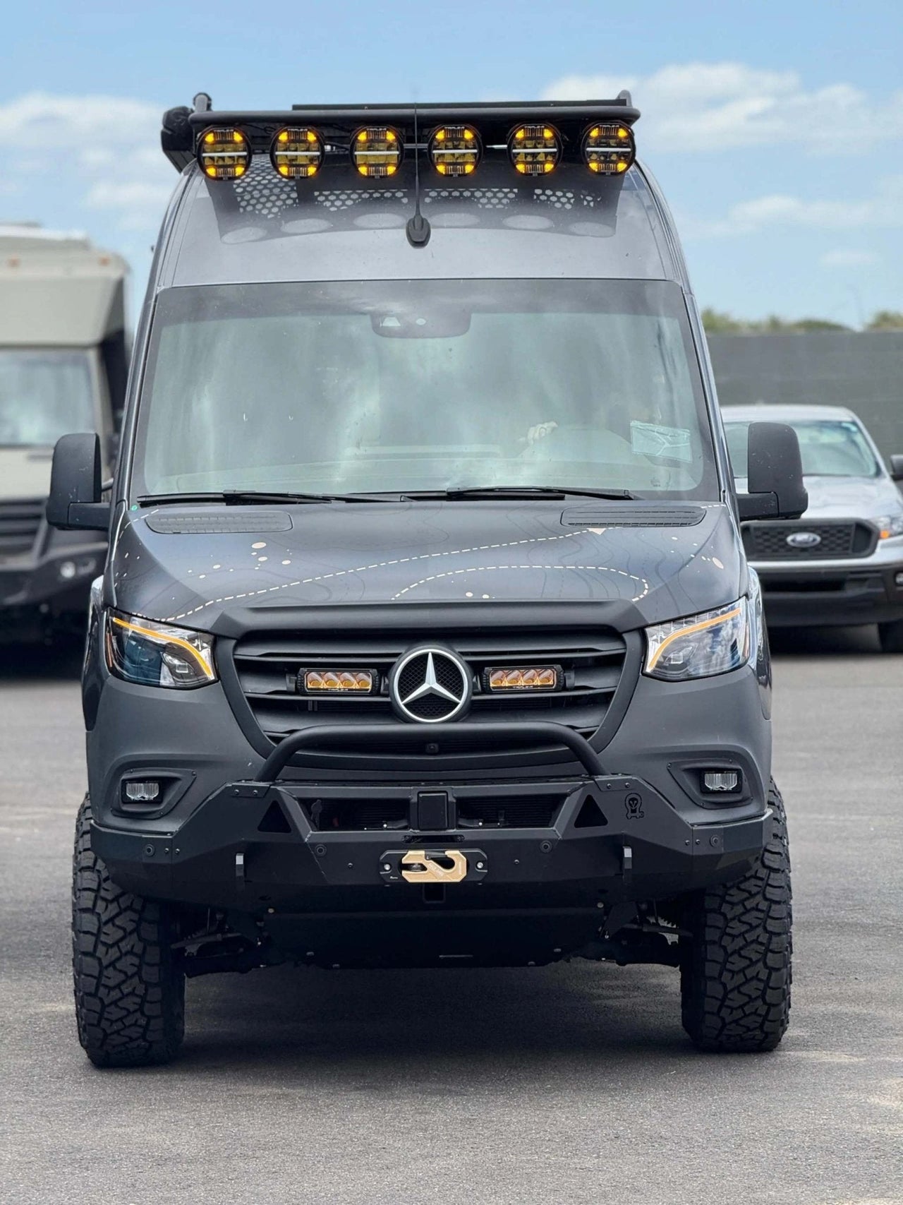 Front view of a black Mercedes Sprinter van equipped with high-output SAE road-legal and off-road fog lights and roof light